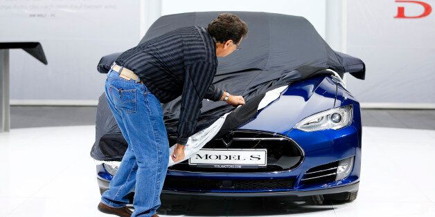 An employee covers a Tesla Model S car during the media day at the Frankfurt Motor Show (IAA) in Frankfurt, Germany, September 14, 2015. Flush with cash and confidence after years of rising sales, German carmakers are used to reaping industry-leading returns. But with Chinese demand abruptly slowing, the profit engine has begun to sputter, overshadowing the glitz of the world's biggest auto show which opens in Frankfurt. REUTERS/Kai Pfaffenbach