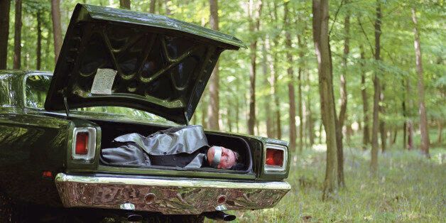 Car in woodland, mature man gagged and bound in boot