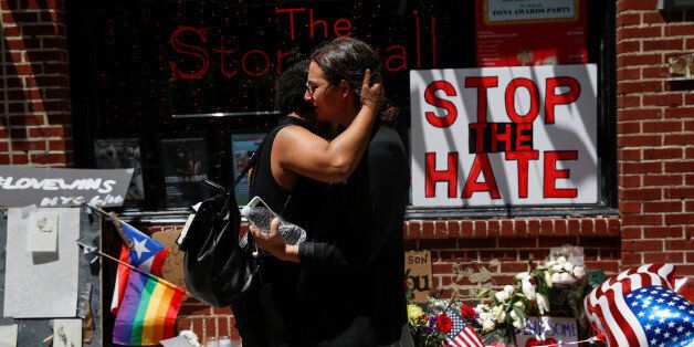 Matti Mejia (L) and Shaina Roberts embrace after laying flowers at a memorial outside The Stonewall Inn remembering the victims of the Orlando massacre in New York, U.S., June 13, 2016.  REUTERS/Shannon Stapleton