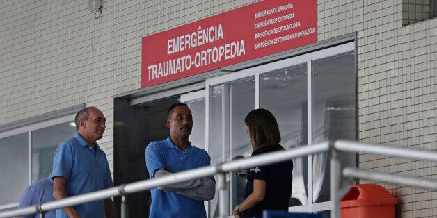 Employees stand in front an emergency entrance at the Souza Aguiar Hospital, in Rio de Janeiro, Brazil, Sunday, June 19, 2016. Brazilian police say armed men stormed the Rio de Janeiro hospital to free a suspected drug trafficker, sparking a shootout with officers, with at least one patient killed, and a nurse and an off-duty policeman wounded. (AP Photo/Silvia Izquierdo)
