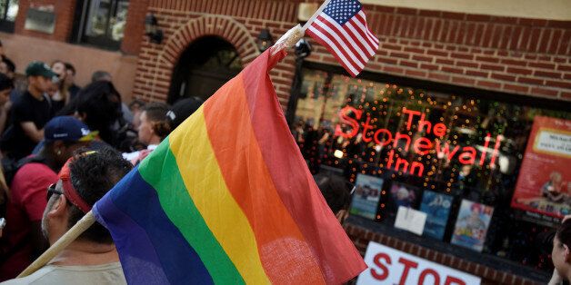 A man carries a gay pride flag at a vigil outside The Stonewall Inn on Christopher Street, considered by some as the center of New York State's gay rights movement, following the shooting massacre at Orlando's Pulse nightclub, in the Manhattan borough of New York, U.S., June 12, 2016. REUTERS/Mark Kauzlarich