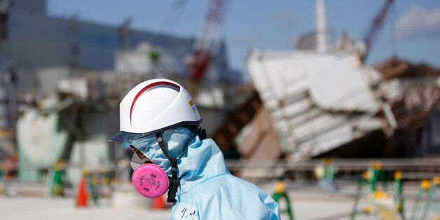 FILE - In this Feb. 10, 2016, file photo, a Tokyo Electric Power Co. (TEPCO) employee, wearing a protective suit and a mask, walks in front of the No. 1 reactor building at the tsunami-crippled Fukushima Dai-ichi nuclear power plant in Okuma, Fukushima Prefecture, northeastern Japan. Five years after a powerful earthquake and tsunami sent the nuclear power plant in the country into multiple meltdowns, cleaning up the mess both onsite and in surrounding towns remains a work in progress. (Toru Hanai/Pool Photo via AP, File)