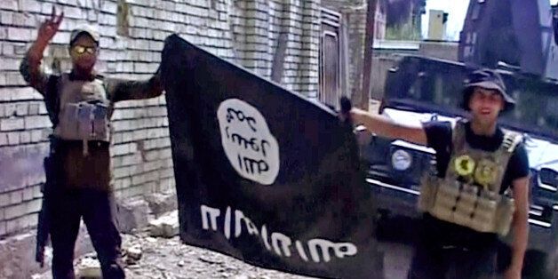 This image made from Associated Press video shows, Iraqi troops turn the Islamic State flag upside down in Fallujah, Iraq, Sunday, June 26, 2016. A senior Iraqi commander declared that the city of Fallujah was