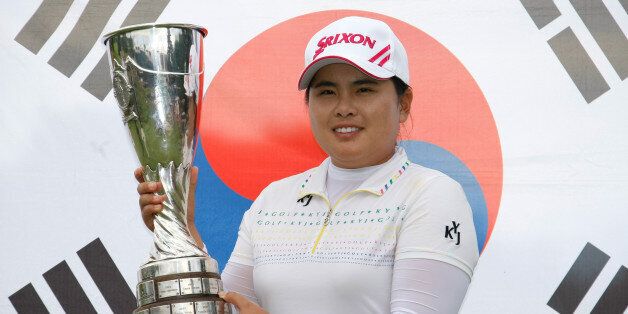 Park In-bee of South Korea holds her trophy in front of the national flag, after winning the Evian Masters women's golf tournament in Evian, eastern France, Sunday, July 29, 2012. (AP Photo/Claude Paris)