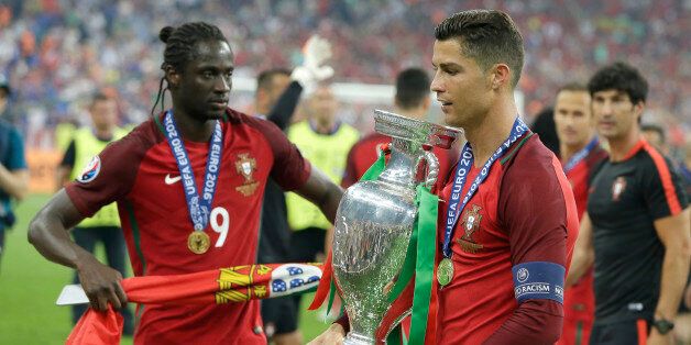 Portugal's Cristiano Ronaldo holds the trophy, next to Eder after winning the Euro 2016 final soccer match between Portugal and France at the Stade de France in Saint-Denis, north of Paris, Sunday, July 10, 2016. (AP Photo/Thanassis Stavrakis)