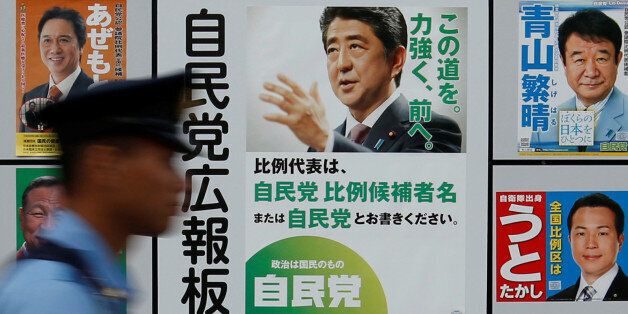 A police officer walks past Japan's ruling Liberal Democratic Party's (LDP) poster (2nd R) for the July 10 upper house election with the image of Shinzo Abe, Japan's Prime Minister and leader of the LDP, and other candidates' posters at the LDP headquarters in Tokyo, Japan July 10, 2016.    REUTERS/Toru Hanai