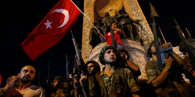 Turkish military stand guard near the the Taksim Square as people wave with Turkish flags in Istanbul, Turkey, July 16, 2016.   REUTERS/Murad Sezer