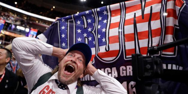 California delegate Jake Byrd reacts as New York delegate Bob Hayssen holds up a Trump flag during the second day session of the Republican National Convention in Cleveland, Tuesday, July 19, 2016. (AP Photo/John Locher)