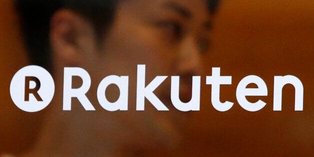 A staff of Rakuten Cafe is seen behind a logo of Rakuten Inc. at a shopping district in Tokyo August 4, 2014. Japan's largest e-commerce company Rakuten Inc posted a 9.9 percent decrease in second quarter operating profit, dragged lower by weaker trading volumes on its Internet finance platform. REUTERS/Yuya Shino (JAPAN - Tags: BUSINESS LOGO)