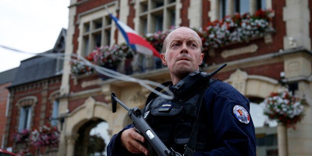 A policeman secures a position in front of the city hall after two assailants had taken five people hostage in the church at Saint-Etienne-du -Rouvray near Rouen in Normandy, France, July 26, 2016. Two attackers killed a priest with a blade and seriously wounded another hostage in a church in northern France on Tuesday before being shot dead by French police.   REUTERS/Pascal Rossignol