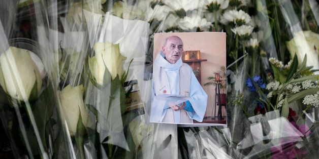 A picture of late Father Jacques Hamel is placed on flowers at the makeshift memorial in front of the city hall closed to the church where an hostage taking left a priest dead the day before in Saint-Etienne-du-Rouvray, Normandy, France, Wednesday, July 27, 2016. The Islamic State group crossed a new threshold Tuesday in its war against the West, as two of its followers targeted a church in Normandy, slitting the throat of an elderly priest celebrating Mass and using hostages as human shields be