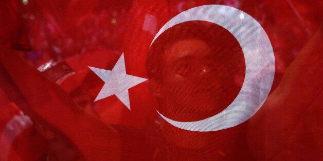 A man holds a Turkish flag during an anti coup rally at Taksim square in Istanbul, Tuesday, July 26, 2016.  Turkey's polarized factions should learn from their mistakes and overcome their antagonism, the main opposition leader Kemal Kilicdaroglu said during an interview with The Associated Press. (AP Photo/Petros Karadjias)