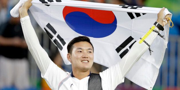 South Korea's Ku Bon-chan holds a National flag after winning the gold medals of the men's team archery competition at the Sambadrome venue during the 2016 Summer Olympics in Rio de Janeiro, Brazil, Saturday, Aug. 6, 2016.(AP Photo/Natacha Pisarenko)