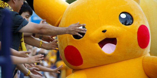 People touch a performer wearing Pokemon's character Pikachu costume during a parade in Yokohama, Japan, August 7, 2016. REUTERS/Kim Kyung-Hoon