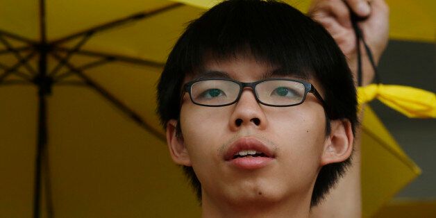 Student leader Joshua Wong, attends a protest outside a court in Hong Kong, Friday, July 17, 2015. Wong along with other three pro-democracy protesters appeared in court on Friday after being charged with obstructing police officers as they took part in an anti-China protest outside the Liaison Office in June, 2014.(AP Photo/Kin Cheung)
