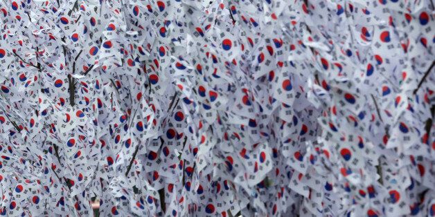 In this Thursday, Aug. 13, 2015, file photo, a woman looks at South Korean national flags hanging on trees to celebrate the upcoming the 70th anniversary of Independence Day, Aug. 15, from Japanese colonial rule at downtown Seoul, South Korea. (AP Photo/Lee Jin-man, File)