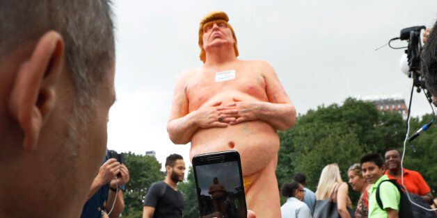 People take photos of a statue of a naked Republican presidential candidate Donald Trump Thursday, Aug. 18, 2016, in New York's Union Square. The statue was removed by New York City Department of Parks & Recreation employees. (AP Photo/Mary Altaffer)