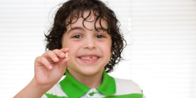 TORONTO, ONTARIO, CANADA - 2011/06/29: Human development stage: Child holding a baby tooth that has just dropped over white background. (Photo by Roberto Machado Noa/LightRocket via Getty Images)