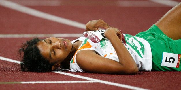 India's Jaisha Orchatteri Puthiya Veetil lies on the track after the women's 5000m final at the 15th Asian Games in Doha December 11, 2006. Veetil took the bronze medal.   REUTERS/Jerry Lampen  (QATAR)