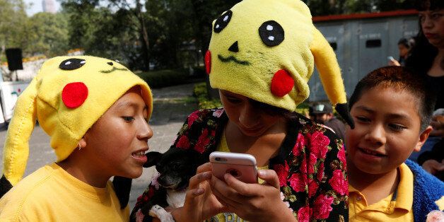Children wearing hats of a Pokemon character, Pikachu, play Pokemon Go during a gathering to celebrate