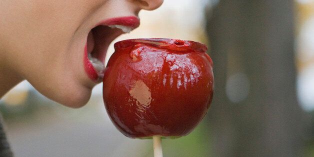 Profile of young woman eating candy apple