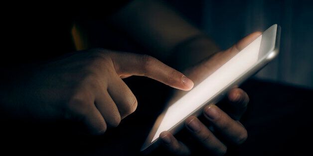 Hand touching digital tablet in darkroom
