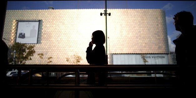 A woman is silhouetted against a department store at Apgujeong luxury shopping district in Seoul, South Korea, November 12, 2015. South Korea's central bank left interest rates at a record low 1.5 percent for a fifth consecutive month, and countered calls for a cut arguing that strong domestic demand could still lead economic recovery despite weak exports.REUTERS/Kim Hong-Ji