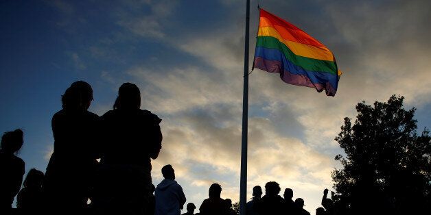 Mourners gather under an LGBT pride flag flying at half-mast for a candlelight vigil in remembrance for mass shooting victims in Orlando, from San Diego, California, U.S. June 12, 2016.  REUTERS/Mike Blake
