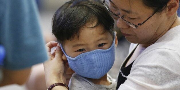 A passenger puts a masks on her son to prevent contracting Middle East Respiratory Syndrome (MERS) at the Incheon International Airport in Incheon, South Korea, June 14, 2015. A South Korean hospital suspended most services on Sunday after being identified as the epicentre of the spread of a deadly respiratory disease that has killed 15 people since being diagnosed in the country nearly four weeks ago.   REUTERS/Kim Hong-Ji