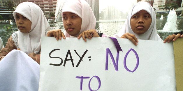 Indonesian women wearing Muslim hijab head scarves hold a sign denouncing calls by Muslim groups encouraging the practice of polygamy among government employees during a protest by a women's rights group in central Jakarta, November 24, 2000. Though Islam allows Muslim men up to four wives the practice is not common and the Indonesian government forbids its employees to have more than one wife.DW/DL