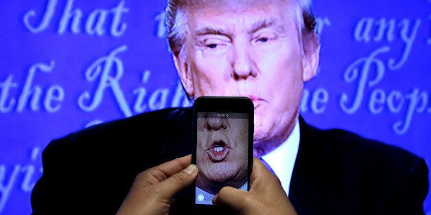 A journalist records a video from screen as Republican U.S. presidential nominee Donald Trump speaks during the first presidential debate with U.S. Democratic presidential candidate Hillary Clinton at Hofstra University in Hempstead, New York, U.S. on September 26, 2016. REUTERS/Carlos Barria/File Photo