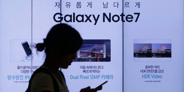 FILE - In this Friday, Sept. 2, 2016, file photo, a woman walks by an advertisement of the Samsung Electronics Galaxy Note 7 smartphone at the company's showroom in Seoul, South Korea. The Federal Aviation Administration said Thursday night, Sept. 8, 2016, that because of recent fire reports involving the Galaxy Note 7 smartphone, passengers shouldnât use or charge one or stow one in checked baggage. The three biggest U.S. airlines: American, Delta and United, said Friday that they were stu