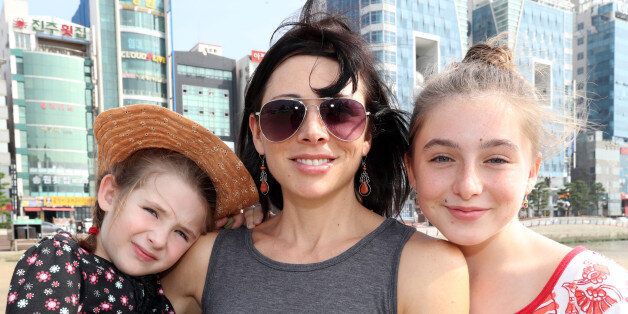 15일 부산 수영구 광안리해수욕장에서 미국인 디애나 루퍼트(38·여·가운데)씨와 두 딸 피오나(11·오른쪽)·스텔라(5·왼쪽) 양이 활짝 웃고 있다.