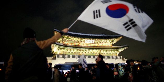 A man waves a national flag as people march toward the Presidential Blue House during a rally demanding President Park Geun-hye to step down in central Seoul, South Korea, November 12, 2016.   REUTERS/Kim Hong-Ji