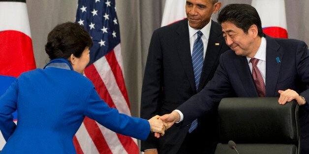 South Korean President Park Geun-hye, left, shakes hands with Japanese Prime Minister Shinzo Abe, right, as President Barack Obama watches, after their meeting at the Nuclear Security Summit in Washington, Thursday, March 31, 2016. (AP Photo/Jacquelyn Martin)