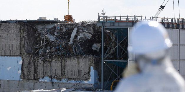 A member of the media, wearing a protective suit and a mask, looks at the No. 3 reactor building at Tokyo Electric Power Co's (TEPCO) tsunami-crippled Fukushima Daiichi nuclear power plant in Okuma town, Fukushima prefecture, Japan February 10, 2016.  REUTERS/Toru Hanai