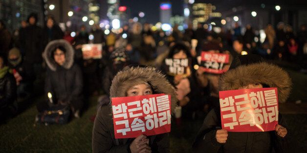 TOPSHOT - A woman hold a placard reading 'Arrest Park Geun-Hye' during a small rally following the impeachment of President Park Geun-Hye, in central Seoul on December 9, 2016.South Korean lawmakers voted to impeach President Park Geun-Hye, stripping away her sweeping executive powers over a corruption scandal and opening a new period of national uncertainty. / AFP / Ed JONES        (Photo credit should read ED JONES/AFP/Getty Images)