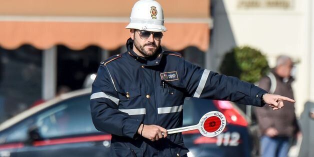 A police officer controls cars and scooters during the limited traffic day, in centeral Rome, on December 29, 2015. A second day with limited traffic of odd and even car plate numbers was enforced in the hope of lowering air pollution. A lack of rainfall has led pollution levels to climb in recent weeks, and has prompted the administration of Rome, to appeal to drivers to respect the rules.    / AFP / ANDREAS SOLARO        (Photo credit should read ANDREAS SOLARO/AFP/Getty Images)