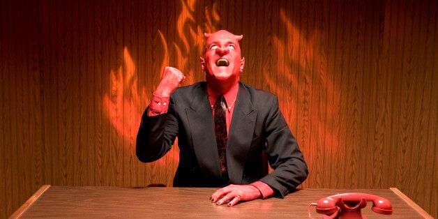 Businessman dressed as devil laughing