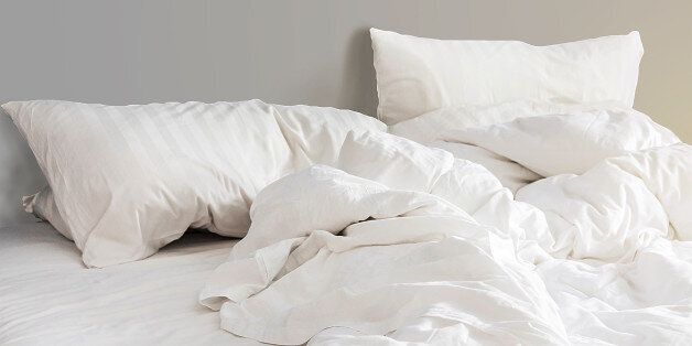 bed and white pillows with wrinkle blanket in bedroom, from sleeping in a long night.