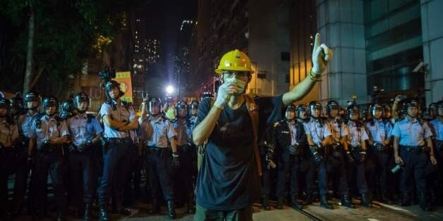 A protester wearing a mask gestures in front of riot police amid ongoing demonstrations in Hong Kong on November 6, 2016.Hong Kong police used pepper spray November 6 to drive back hundreds of protesters angry at China's decision to intervene in a row over whether two pro-independence lawmakers should be barred from the city's legislature. In chaotic scenes reminiscent of mass pro-democracy protests in 2014, demonstrators charged metal fences set up by police outside China's liaison office in th