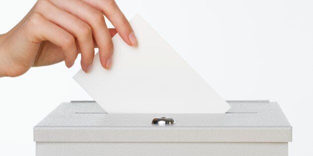 Close up of woman's hand putting card in box with slot