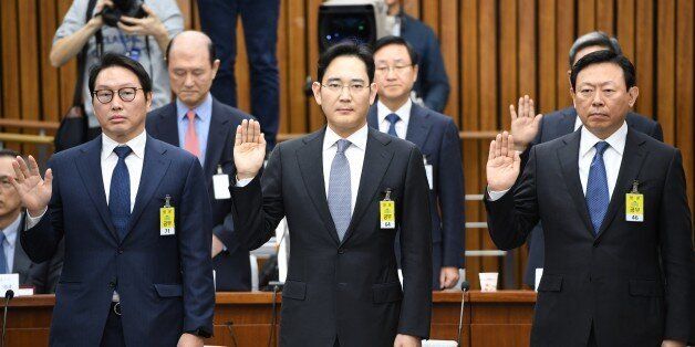 (L-R) SK Group chairman Chey Tae-Won, Samsung Group's heir-apparent Lee Jae-Yong and Lotte Group Chairman Shin Dong-Bin take an oath during a parliamentary probe into a scandal engulfing President Park Geun-Hye at the National Assembly in Seoul on December 6, 2016. The publicity-shy heads of South Korea's largest conglomerates faced their worst nightmare on December 6, as they were publicly grilled about possible corrupt practises before an audience of millions. / AFP / POOL / JUNG YEON-JE