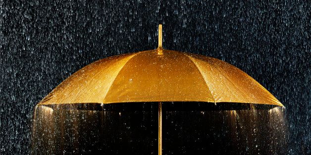 Conceptual photograph of a golden umbrella with rain.