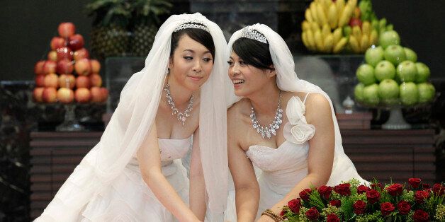 You Ya-ting (L) and Huang Mei-yu cast their stamps during their symbolic same-sex Buddhist wedding ceremony at a temple in Taoyuan county, northern Taiwan, August 11, 2012. The 30-year-old lesbian couple tied the knot after dating for seven years on Saturday in Taiwan's first same-sex Buddhist wedding. They hope this wedding will help make Taiwan the first place in Asia to legalise same-sex marriage. REUTERS/Pichi Chuang (TAIWAN - Tags: SOCIETY TPX IMAGES OF THE DAY)