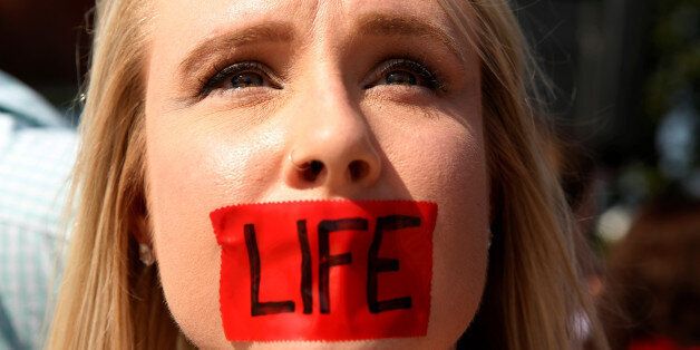 An anti-abortion protester with tape over her mouth demonstrates outside the U.S. Supreme Court before the court handed a victory to abortion rights advocates, striking down a Texas law imposing strict regulations on abortion doctors and facilities in Washington June 27, 2016. REUTERS/Kevin Lamarque