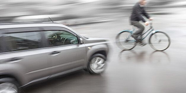 Dangerous city traffic situation with a cyclist and cars in motion blur