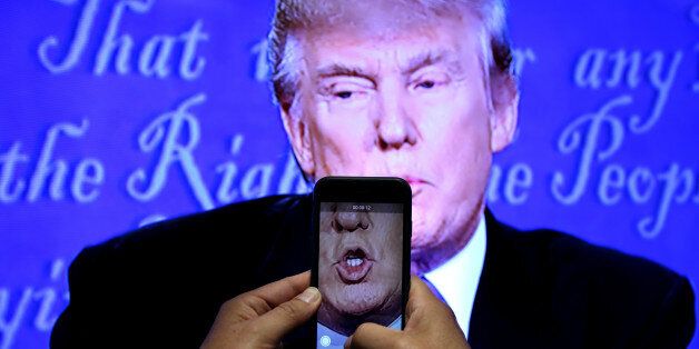 A journalist records a video from screen as Republican U.S. presidential nominee Donald Trump speaks during the first presidential debate with U.S. Democratic presidential candidate Hillary Clinton at Hofstra University in Hempstead, New York, U.S., September 26, 2016. REUTERS/Carlos Barria