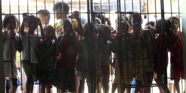 Children wait at the gates for free meals during a feeding program given by volunteers from a religious group at a slum area in Tondo, metro Manila  February 23, 2016. The World Bank on Saturday approved $450 million of funding for the Philippines' flagship anti-poverty program, which will provide basic healthcare and education to millions of families until 2019.  REUTERS/Romeo Ranoco                        TPX IMAGES OF THE DAY