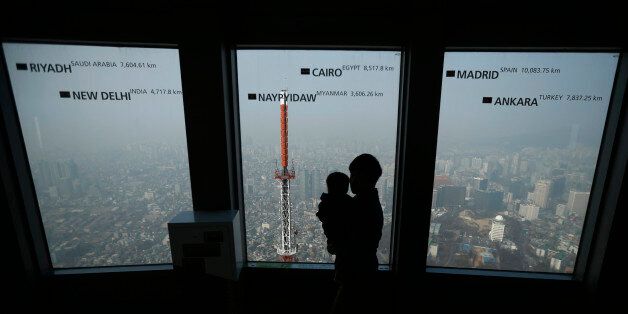A man holds his baby while viewing central Seoul shrouded in heavy haze at an observation platform at